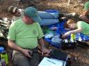 Star Scout Mason Turner, KK4HOR, checks out some gear while Scoutmaster Chris Anderson makes a contact in Canada using his Yaesu FT-857D transceiver and Buddipole antenna while backpacking in Ocala National Forest. Assistant Scoutmaster Ryan Smith, KK4JLG, listens in. [Karen Anderson, KK4ENM, photo]